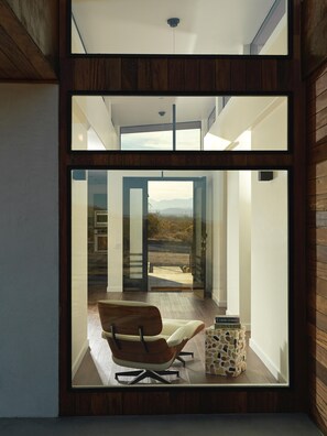 Un intérieur moderne avec une grande baie vitrée, un plancher en bois et un fauteuil en cuir.