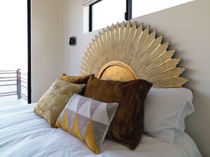 Un lit doté d’une grande tête de lit décorative et de plusieurs oreillers.