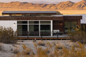 A modern building with large windows, a flat roof, and a desert landscape in the background. - Panoramic Heaven - Luxury Property Pool & Spa (Joshua Tree)