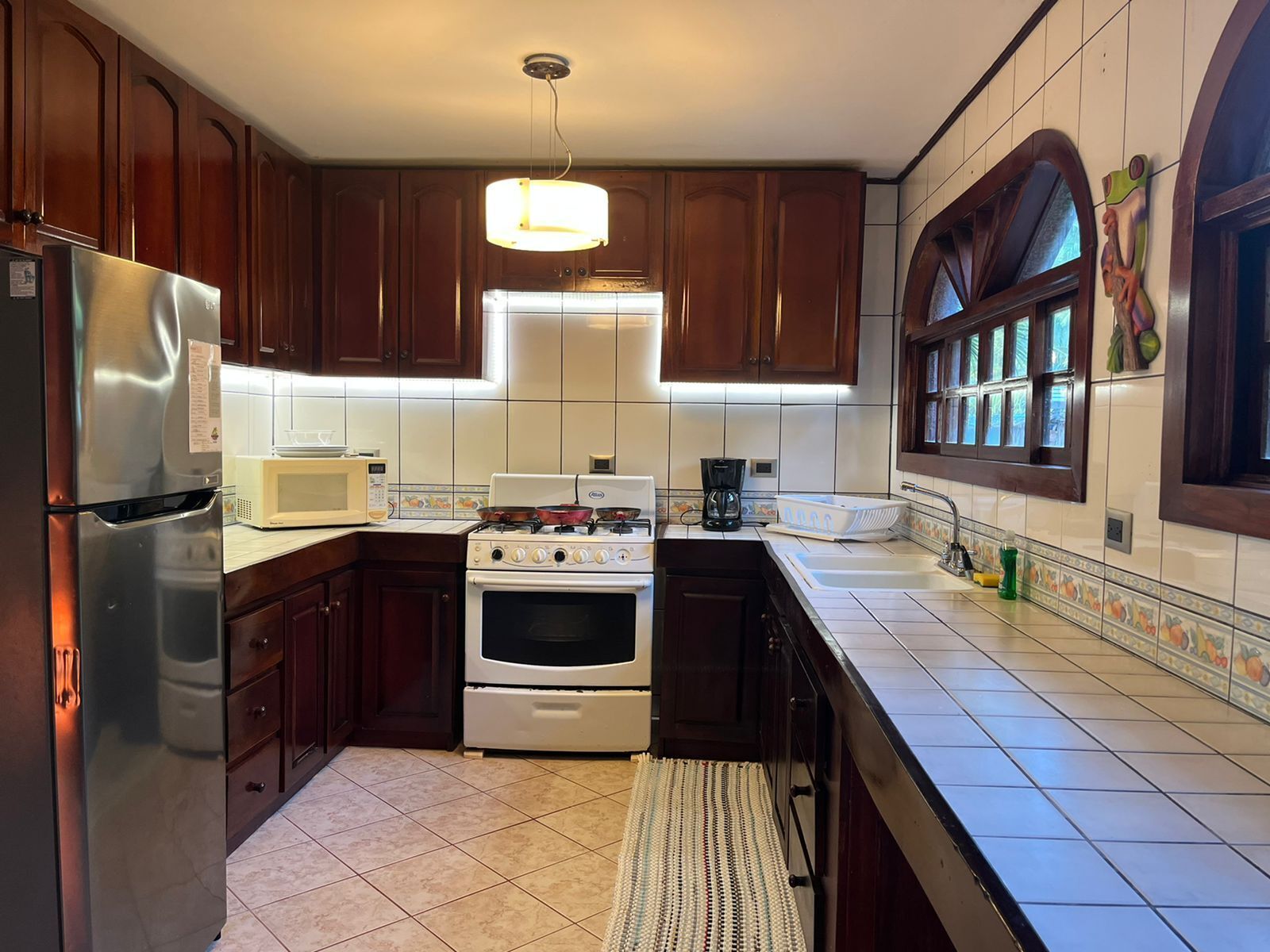 Une cuisine avec des meubles de rangement en bois, un réfrigérateur en acier inoxydable, une cuisinière blanche et un four à micro-ondes.