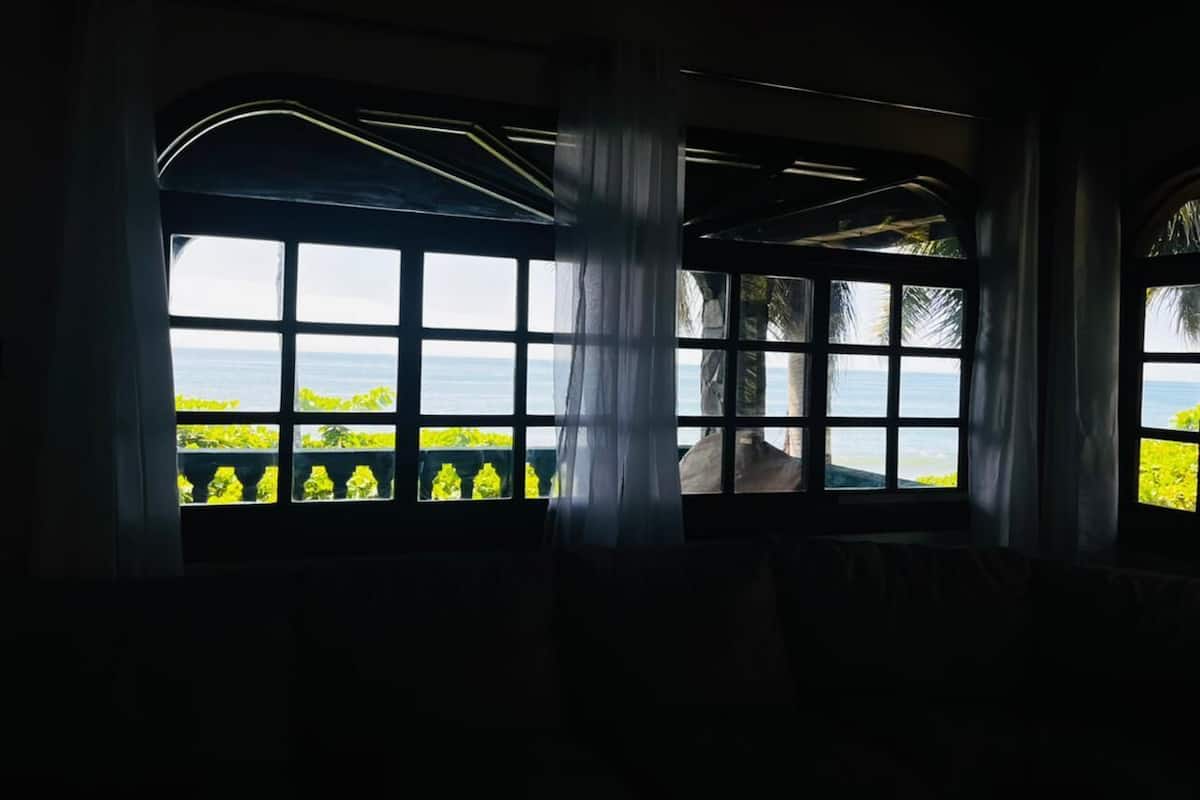 A room with large windows overlooking a body of water and greenery.