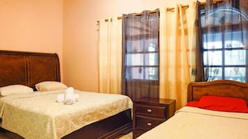 A hotel room with two beds, a wooden headboard, a nightstand, and a window with curtains.