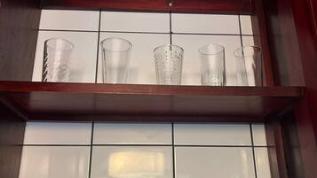 Estante na cozinha com diversos copos e canecas de cerâmica.