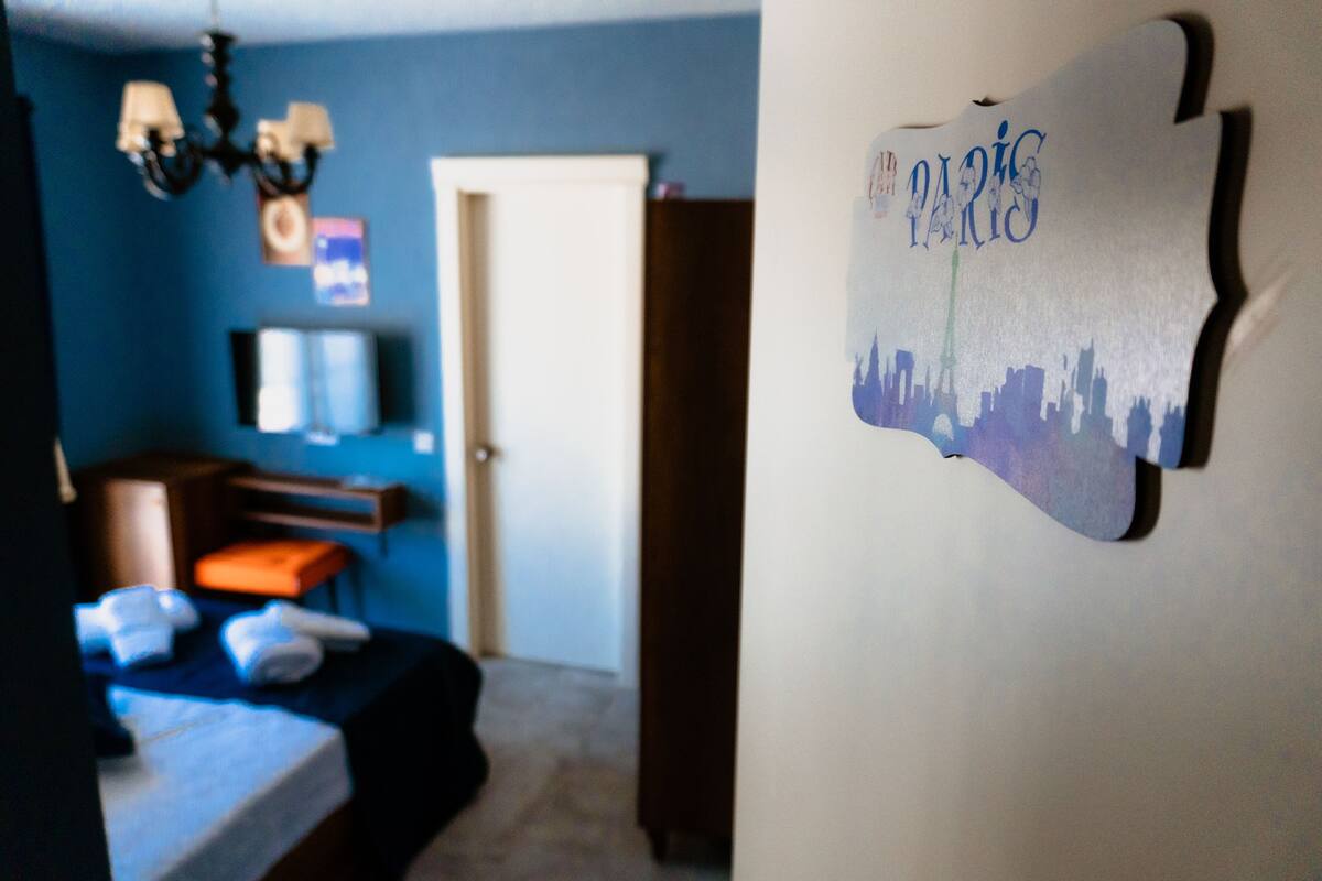 Una habitación con cama, cómoda, silla y un adorno en la pared.