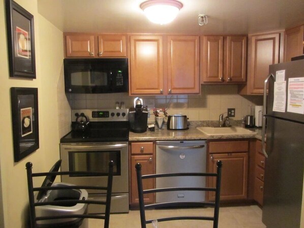 A kitchen with wooden cabinets, a microwave, stove, dishwasher, and a refrigerator.