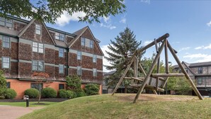A brick building with multiple windows and a swing set in the foreground. - Week of July 4!  Beautiful 2 bedroom unit in downtown Newport, RI  (Newport)