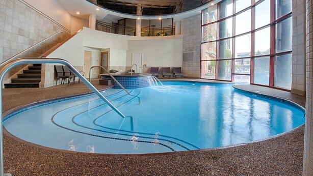 An indoor swimming pool with a pebble-lined edge, a staircase leading to an upper level, and large windows providing natural light. - Week of July 4!  Beautiful 2 bedroom unit in downtown Newport, RI  (Newport)