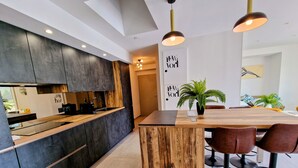 Een moderne keuken met donkere kastjes, een houten kookeiland en een eetgedeelte met barstoelen.