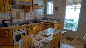 Eine Küche mit einer zentralen Kochinsel, gelben Stühlen und einem Esstisch.