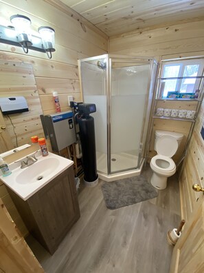 Une salle de bain compacte comprenant un lavabo, des toilettes et une douche à parois de verre.