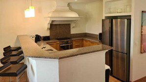 A modern kitchen with a central island, stainless steel appliances, and bar stools.