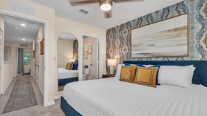 A bedroom with a large bed, a ceiling fan, a wall-mounted painting, and a hallway leading to another room. - *New Construction Luxury Townhome 3mi to downtown* (saint augustine)