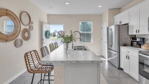 A modern kitchen with white cabinets, stainless steel appliances, and a marble countertop. - *New Construction Luxury Townhome 3mi to downtown* (saint augustine)