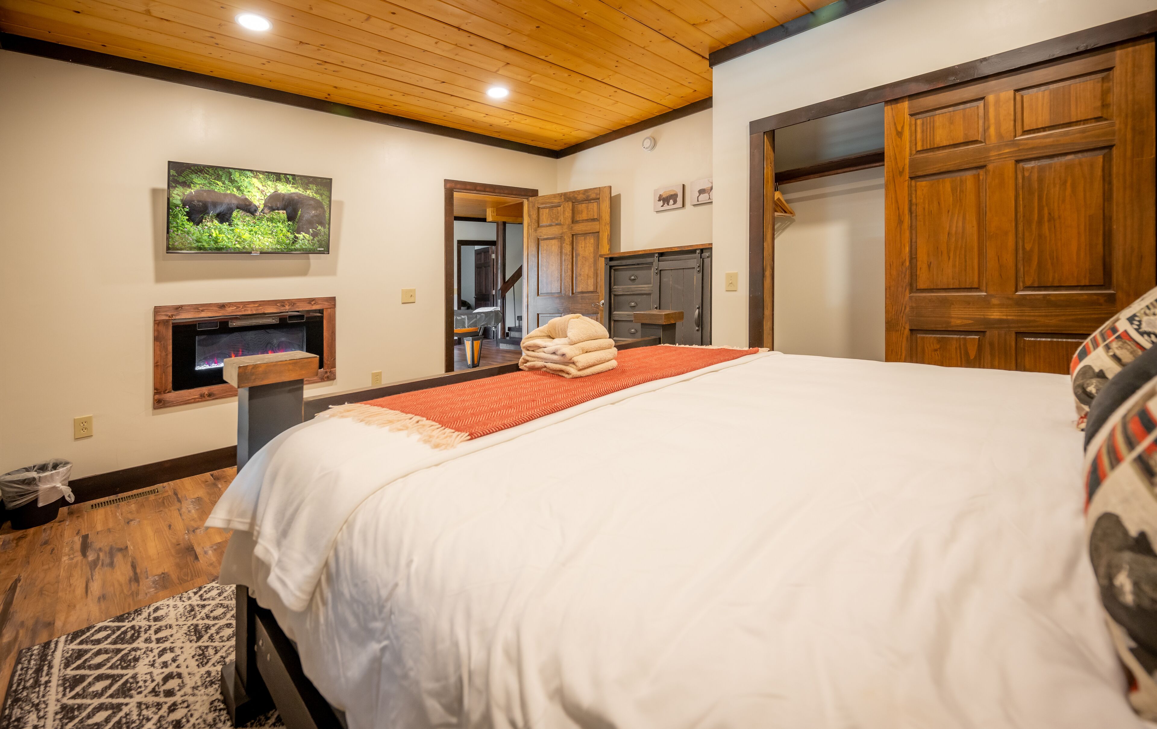 A hotel room with a large bed, a fireplace, wooden doors, and a mirror.