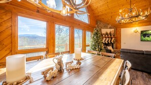 A wooden interior with a large dining table, a Christmas tree, and a fireplace. - Luxurious Cabin / Theater / Game Room / Hot Tub / Large Deck / Panoramic View (Sevierville)