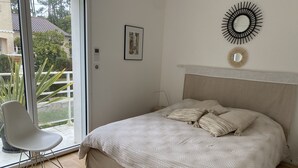 Un dormitorio con una cama, una silla y vistas al exterior.