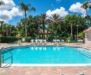 Una piscina circondata da palme e lettini, con un gazebo sullo sfondo.