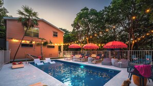 A swimming pool with lounge chairs and umbrellas, surrounded by a house and trees. - NEW!The Hideaway~Pool~Pickleball~Putt-Putt~Kayaks! (Marathon)