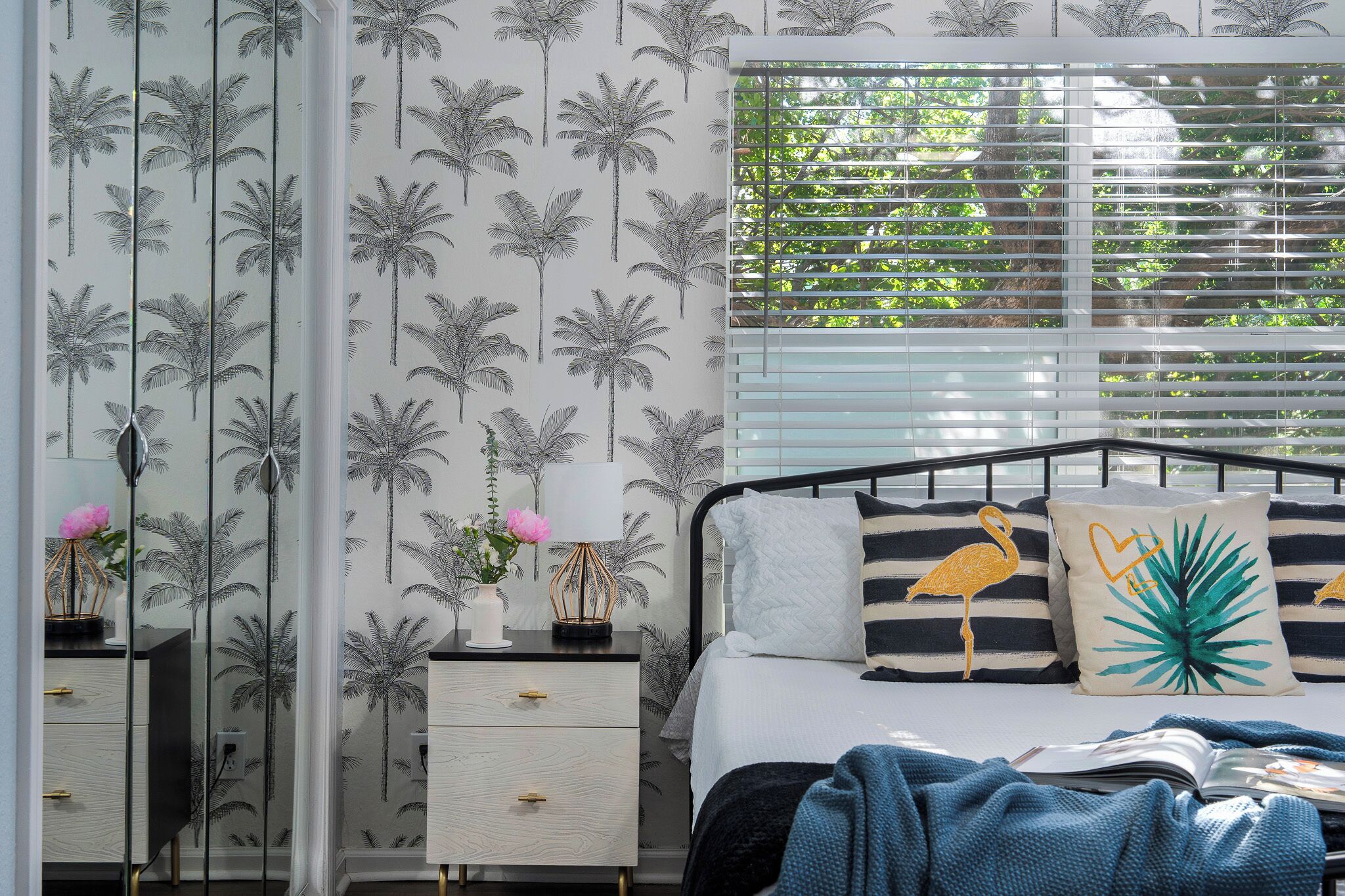 A bedroom with a bed, nightstands, and a window with blinds.