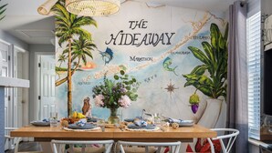 A dining area with a mural titled "The Hideaway Marathon," featuring tropical elements and islands. - NEW!The Hideaway~Pool~Pickleball~Putt-Putt~Kayaks! (Marathon)