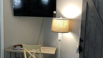 Une chambre dotée d’un téléviseur à écran plat fixé au mur, d’un bureau avec une chaise, d’une lampe et d’une porte coulissante de style rustique.