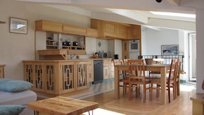 Een ruime keuken met houten kasten, een eethoek met stoelen, en uitzicht op het omliggende landschap.