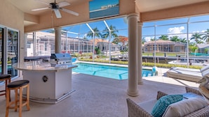 Un espace aménagé au bord de la piscine, comprenant un bar, des chaises longues et offrant une vue sur la piscine et les environs.