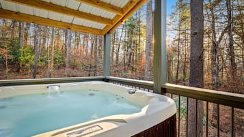 Un jacuzzi en un espacio exterior cubierto con vistas a un bosque.