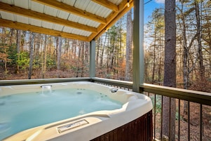 A hot tub in a covered outdoor area with a view of a forest.