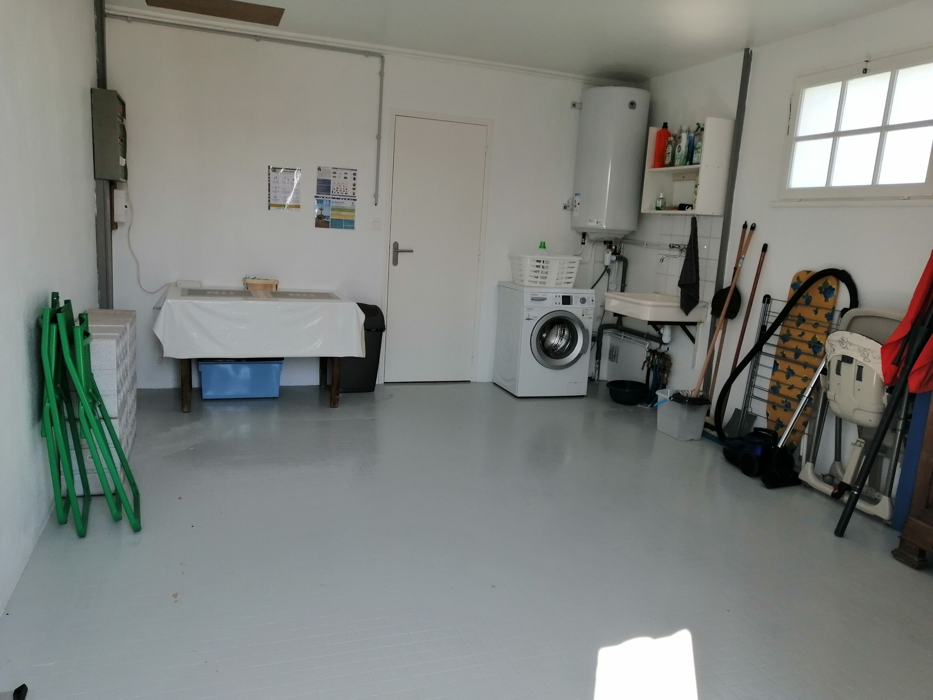 A laundry room with a washing machine, a sink, and a window.