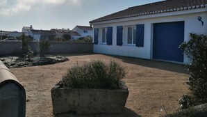 A residential building with a blue garage door, a white exterior, and a tiled roof. - Detached house near beach and shops (Barbâtre)