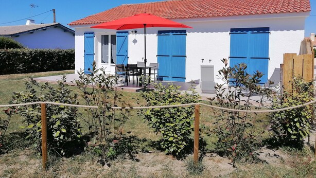 A white building with red-tiled roof, blue shutters, and a red umbrella. - Detached house near beach and shops (Barbâtre)
