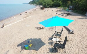 Une plage avec un parasol bleu, une table et des chaises.