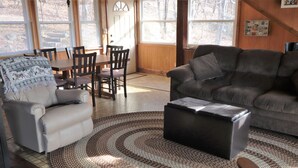 Un salon avec un canapé gris, un tapis à motifs et un coin repas doté de meubles en bois.