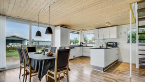 Uma cozinha moderna com armários brancos, uma ilha central e luminárias pendentes.