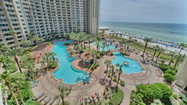 Ein Hotel mit mehreren Schwimmbecken, Palmen und Blick auf den Strand.