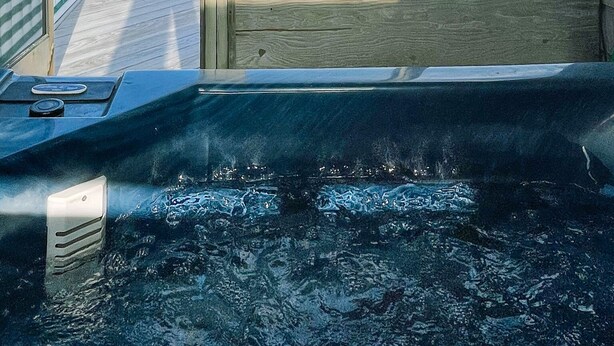 Ein Zimmer mit Blick auf den Strand, einer Holzterrasse und einem Whirlpool.