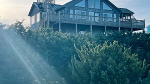 Ein großes, mehrstöckiges Holzhaus mit Balkon, umgeben von dichtem Grün.
