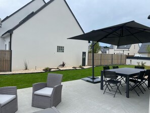 A patio area with outdoor furniture, including a table and chairs, and a large umbrella providing shade.