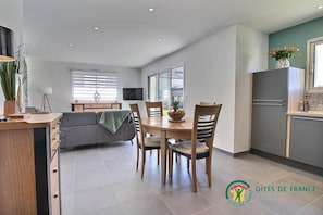 A modern apartment with a dining area, kitchen, and living space.
