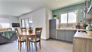 Une cuisine moderne avec des meubles de couleur grise, une table à manger en bois et une plante verte.