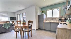 Una cocina moderna con gabinetes grises, una mesa de comedor de madera y una planta verde.