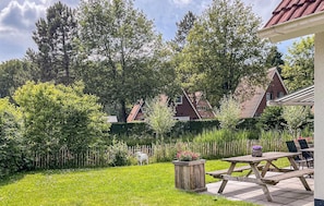 Enjoy outdoor dining or relaxation in a serene natural setting surrounded by trees and shrubs.
