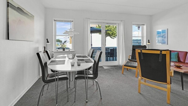 A modern room with a round table, chairs, a sofa, and a painting on the wall. - Cozy apartment in Rudkøbing (Rudkøbing)