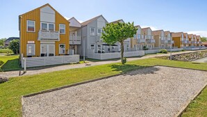 A row of modern, multi-story residential buildings with balconies, a gravel pathway, and a small tree in the foreground. - Cozy apartment in Rudkøbing (Rudkøbing)