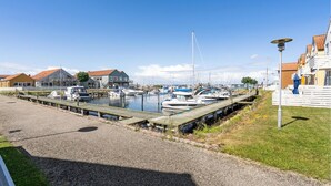 A marina with boats docked, a wooden walkway, and buildings with red roofs. - Cozy apartment in Rudkøbing (Rudkøbing)