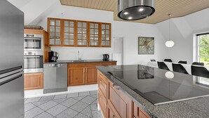 Een moderne keuken met houten kasten, roestvrijstalen apparatuur en een groot eiland.