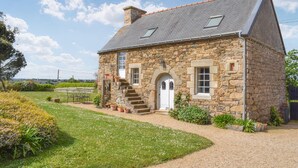 A stone house with a sloped roof, a white door, and a small set of stairs leading to the entrance. - Stunning home in Pleudaniel (Pleudaniel)