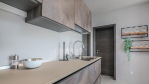 Una cocina moderna con una isla grande, un lavamanos de acero inoxidable y una campana extractora empotrada.