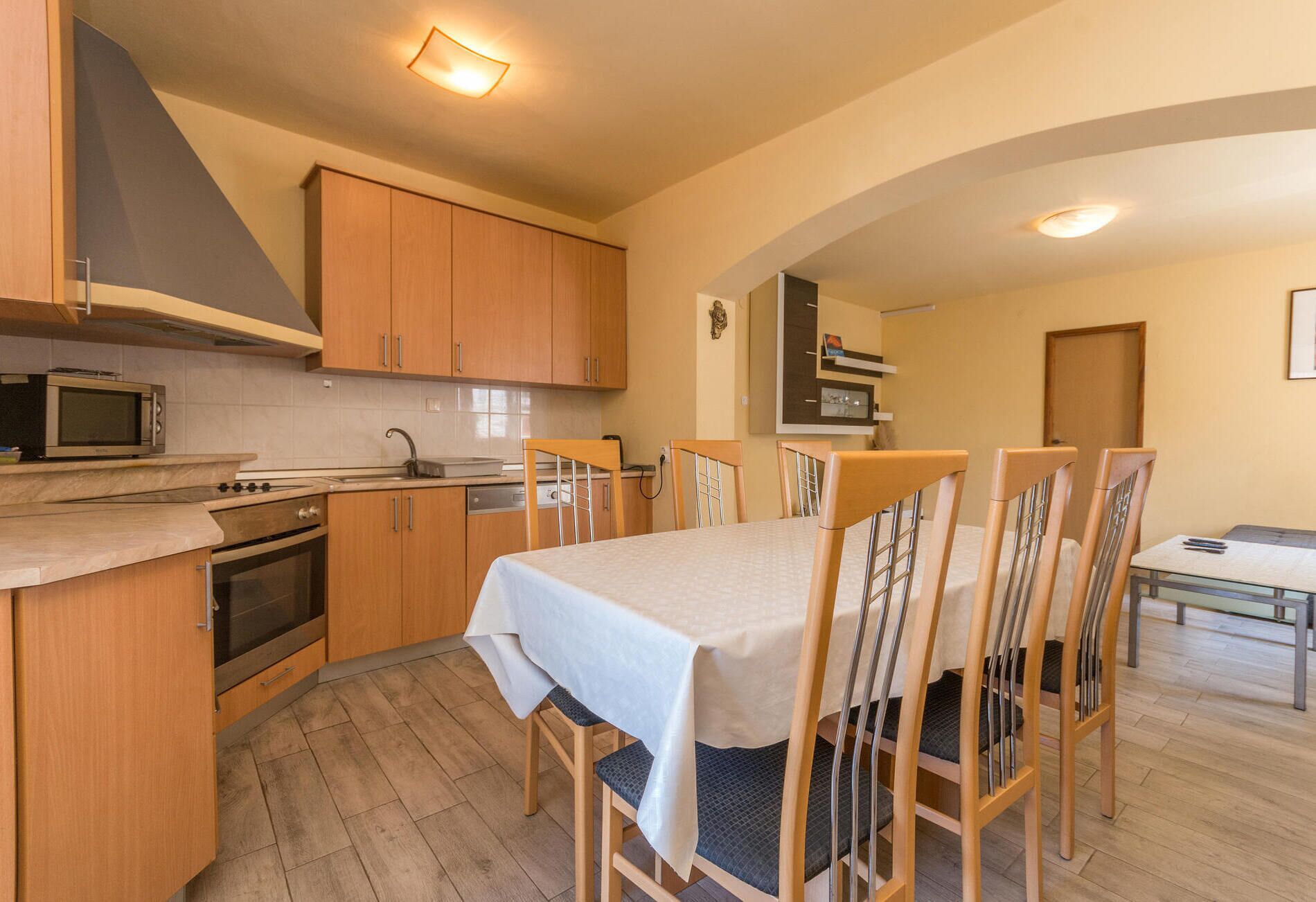 A compact kitchen with wooden cabinets, a microwave, a stove, and a dining area with a table and chairs.